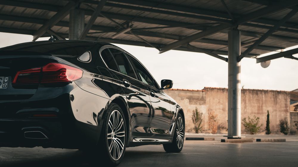 Black BMW executive sedan parked under a covered portico